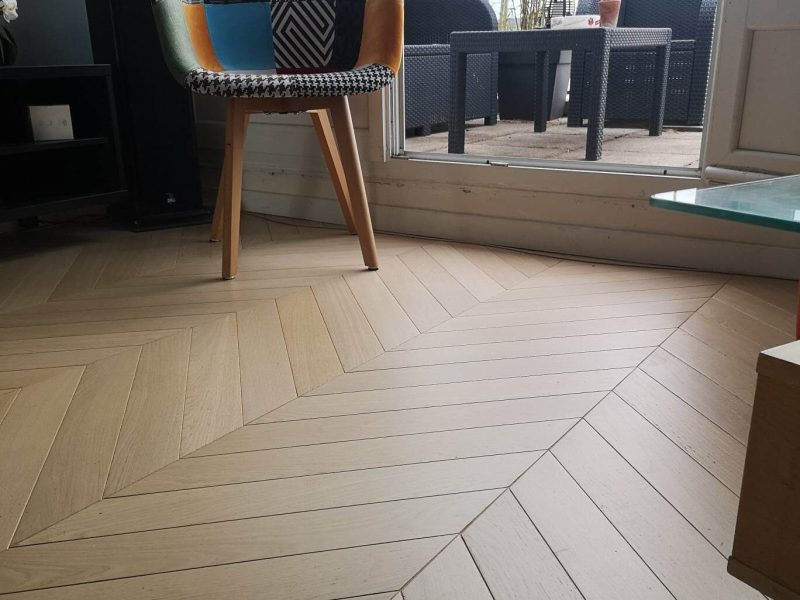 Photo de salon montrant la réalisation d'une pose chevronnée en point de Hongrie - brut vernis mat
