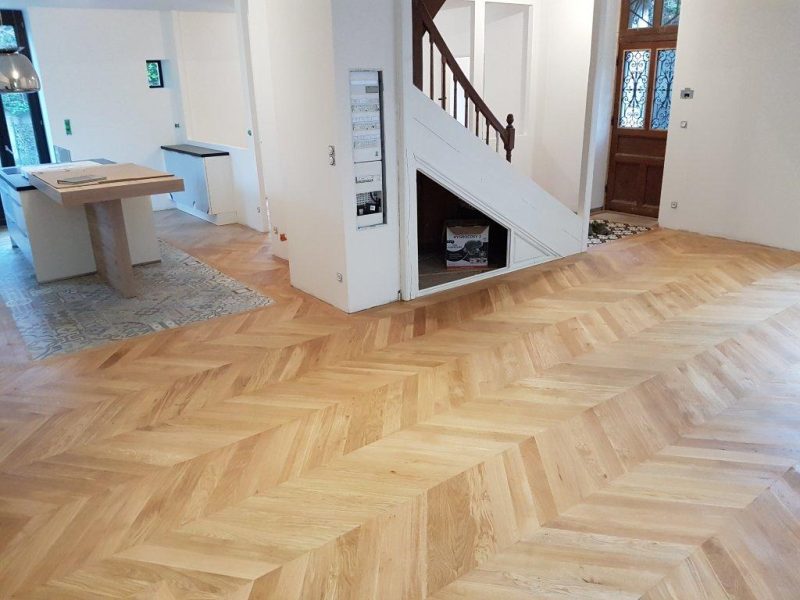 Photo d'une cuisine ouverte sur salon montrant la réalisation de pose de parquets avec incrustation d'un sol lvt en dessous de l'îlot central - pose en point de Hongrie
