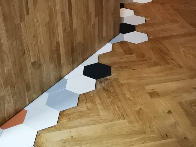 Photo d'un cuisine salon montrant la réalisation de pose de parquets en incrustation avec du carrelage en nids d'abeille