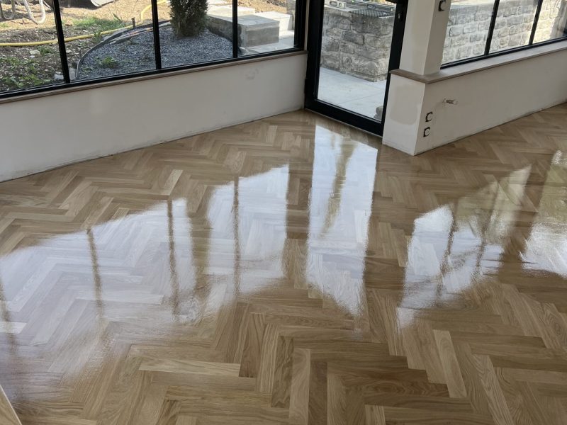 Photo d'une extension montrant la réalisation d'une pose en bâton rompus - couche de vernis fraichement posée