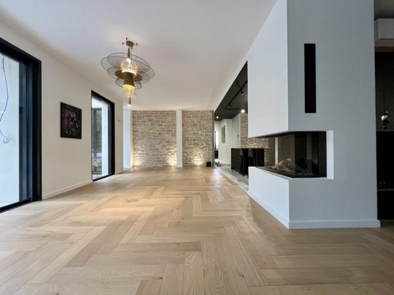 Photo de salon montrant la réalisation d'une pose chevronnée en Bâton Rompus - brut vernis mat